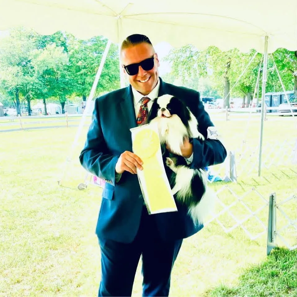 Dan holding a Japanese Chin with award ribbons